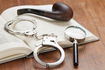 handcuffs, magnifying glass and pipe over an open book